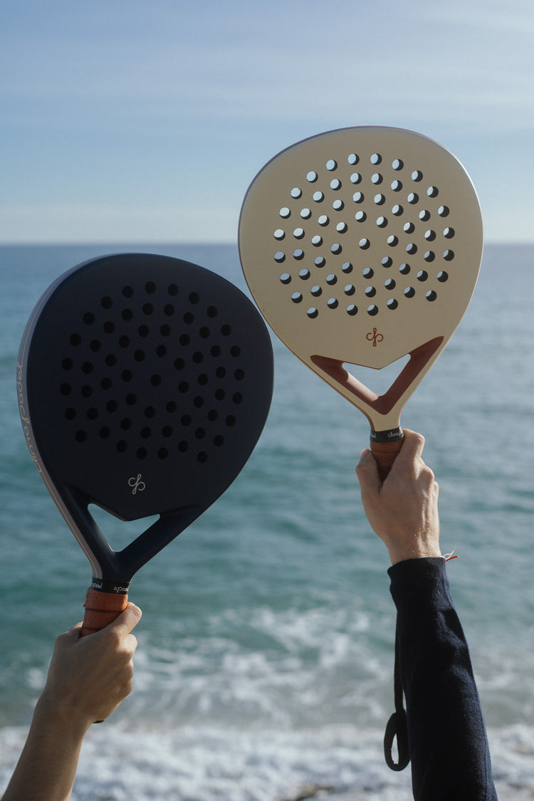 Two Clima rackets held up against the sea