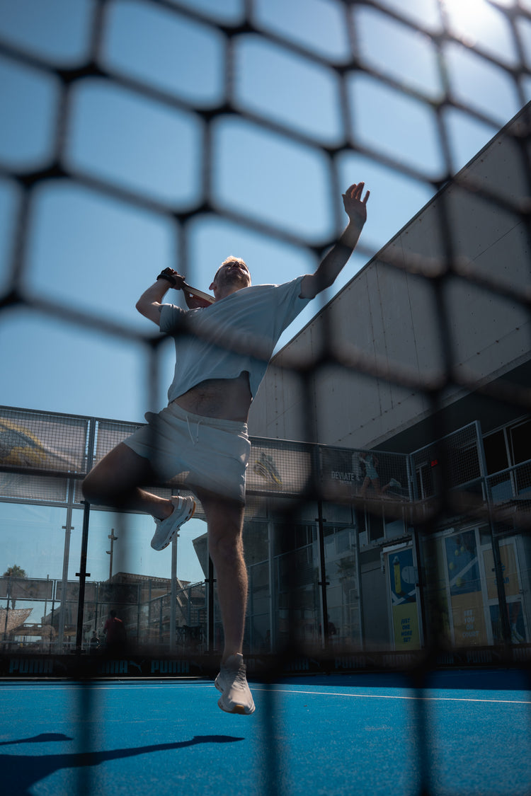 Player leaping for a smash through the court netting